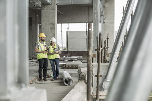 Frau in Arbeitsschutzkleidung und Bauarbeiter auf einer Baustelle - ZEF007850