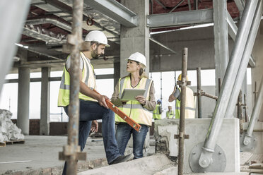 Frau in Arbeitsschutzkleidung und Bauarbeiter diskutieren auf einer Baustelle - ZEF007851