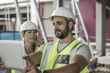 Frau in Arbeitsschutzkleidung und Bauarbeiter auf einer Baustelle - ZEF007855