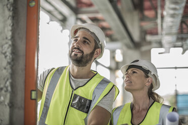 Frau mit Bauarbeiter bei der Wasserwaage auf der Baustelle - ZEF007857