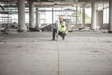 Construction worker using tape measure in construction site - ZEF007866