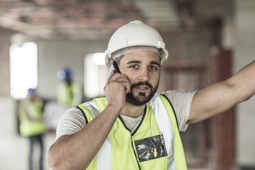 Bauarbeiter telefoniert auf einer Baustelle mit seinem Handy - ZEF007871