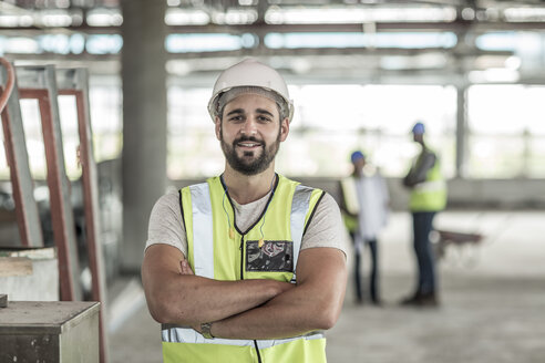 Porträt eines selbstbewussten Bauarbeiters auf einer Baustelle - ZEF007873