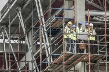 Bauarbeiter und Architekten mit Bauplan auf einem Baugerüst - ZEF007887