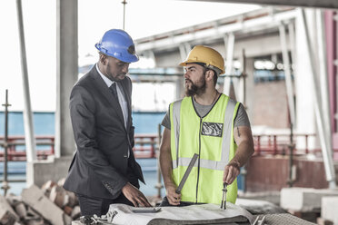 Bauarbeiter und Geschäftsmann unterhalten sich auf der Baustelle - ZEF007890