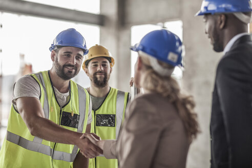 Construction worker and executive shaking hands in construction site - ZEF007895