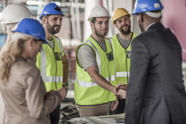 Bauarbeiter und leitender Angestellter schütteln sich auf einer Baustelle die Hände - ZEF007897