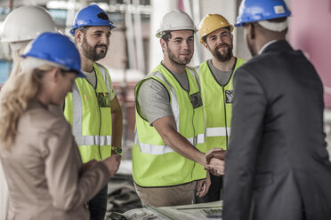 Construction worker and executive shaking hands in construction site - ZEF007897