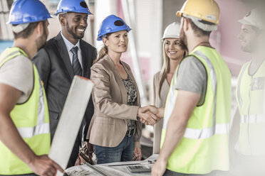 Construction worker and executive shaking hands in construction site - ZEF007899