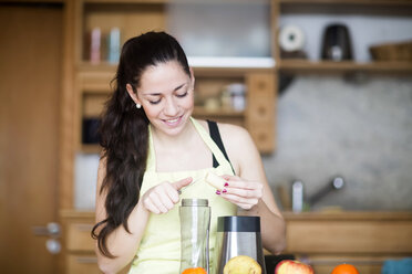 Smiling woman preparing food in her kitchen - SGF001997