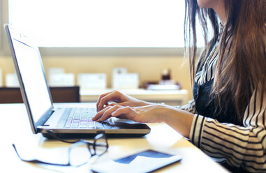 Businesswoman at her desk working with laptop, close-up - MGOF001224