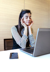 Portrait of businesswoman with closed eyes having a break at her desk - MGOF001227