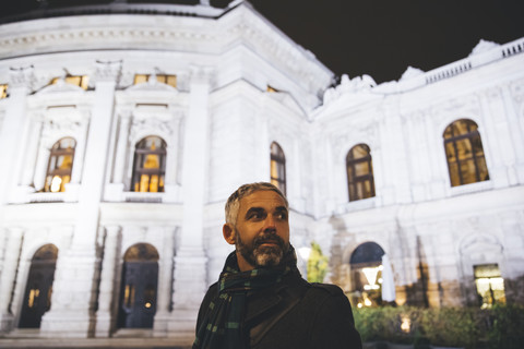 Österreich, Wien, Porträt eines Mannes vor dem Burgtheater bei Nacht, lizenzfreies Stockfoto