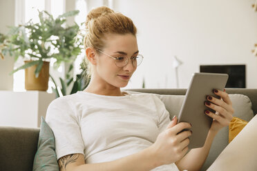 Junge Frau zu Hause, Blick auf ein digitales Tablet - MFF002578