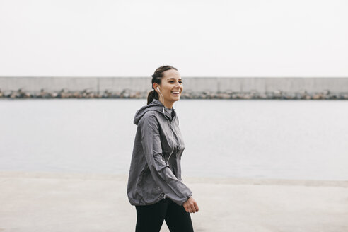 Spain, Barcelona, jogging woman with headphones at harbour - EBSF001217