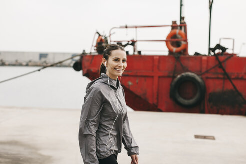 Spanien, Barcelona, joggende Frau mit Kopfhörern am Hafen - EBSF001218
