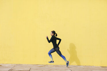 Spanien, Barcelona, joggende Frau vor gelber Wand - EBSF001221