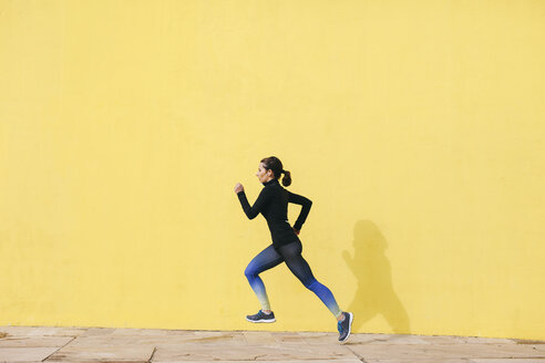 Spain, Barcelona, jogging woman in front of yellow wall - EBSF001221