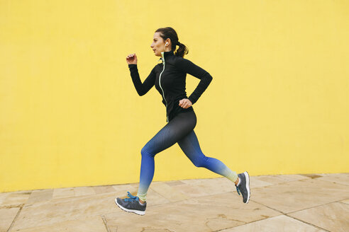 Spain, Barcelona, jogging woman in front of yellow wall - EBSF001225