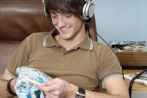 Porträt eines lächelnden Teenagers mit Kopfhörern und Handarbeiten, lizenzfreies Stockfoto