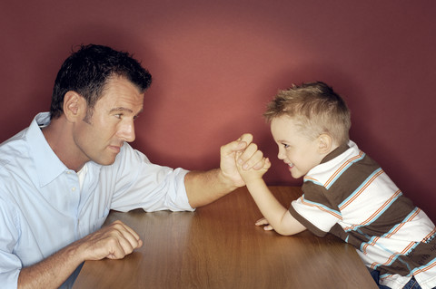 Kleiner Junge beim Armdrücken mit seinem Vater, lizenzfreies Stockfoto