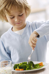 Portrait of smiling blond boy eating broccoli - GUFF000203