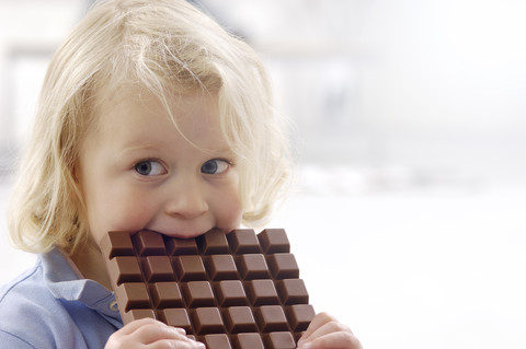 Porträt eines kleinen blonden Mädchens mit Schokoriegel, lizenzfreies Stockfoto