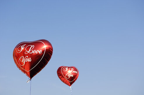 Zwei rote herzförmige Luftballons vor blauem Himmel - GUFF000215