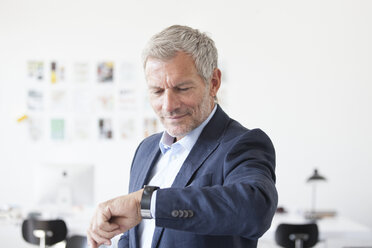 Businessman in office checking the time - RBF003996