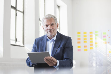 Porträt eines Geschäftsmannes im Büro, der ein digitales Tablet hält - RBF004002