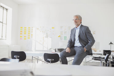 Businessman in office sitting on desk - RBF004010