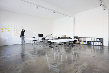 Businessman standing in conference room at wall - RBF004016