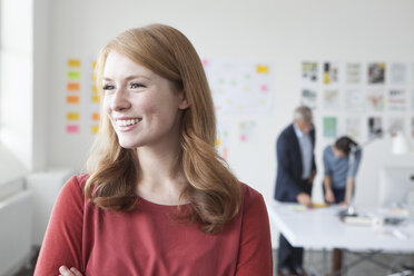 Smiling young woman in office looking away - RBF004019