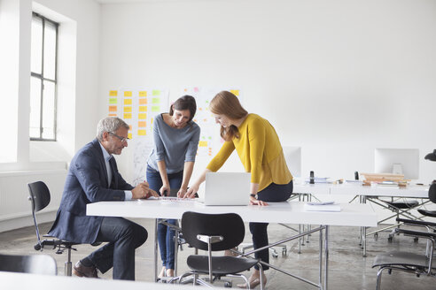 Geschäftsmann und zwei Frauen im Büro bei einem Treffen - RBF004035