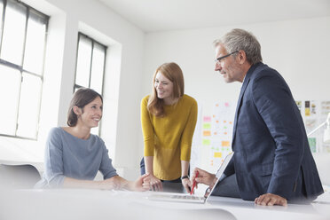 Geschäftsmann und zwei Frauen im Büro bei einem Treffen - RBF004036