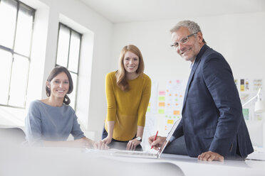 Porträt eines lächelnden Geschäftsmannes und zweier Frauen im Büro - RBF004037