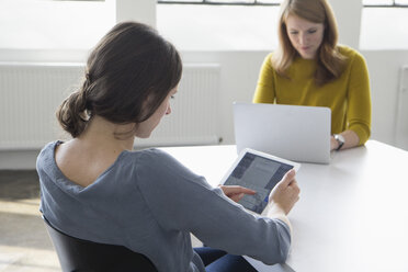 Zwei Frauen in einem Konferenzraum mit digitalem Tablet und Laptop - RBF004041