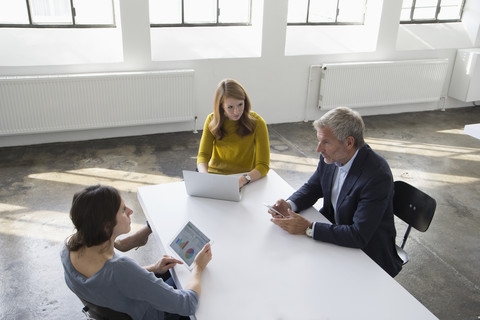 Geschäftsmann und zwei Frauen in einem Konferenzraum bei einer Besprechung, lizenzfreies Stockfoto