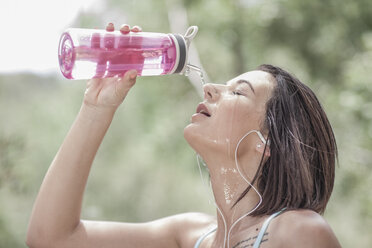 Young sportswoman pouring water over her face - ZEF007924