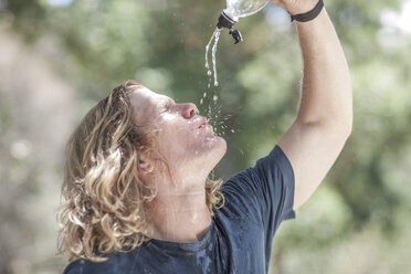 Young man pouring water over his face - ZEF007927