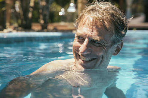 Brasilien, Porto Seguro, Porträt eines lächelnden Mannes in einem Schwimmbad, der etwas beobachtet - MFF002610