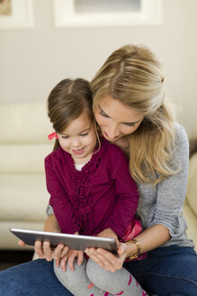 Mutter und ihre kleine Tochter schauen auf ein digitales Tablet - SHKF000442