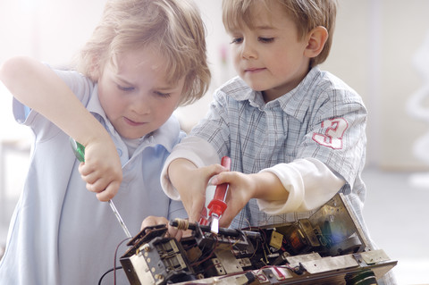 Zwei kleine Jungen zerlegen ein altes Radio, lizenzfreies Stockfoto
