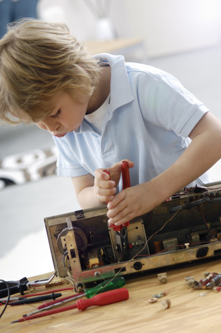 Kleiner Junge beim Zerlegen eines alten Radios, lizenzfreies Stockfoto