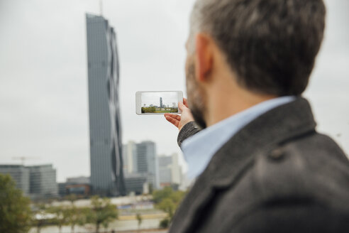 Österreich, Wien, Geschäftsmann, der die DC-Türme mit seinem Smartphone fotografiert - AIF000214