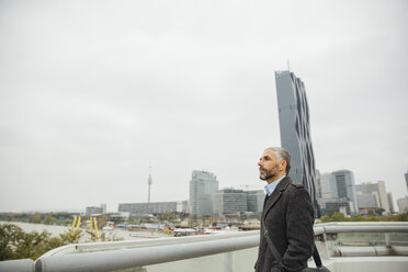 Austria, Vienna, businessman standing on Reichsbruecke in front of DC Towers - AIF000215