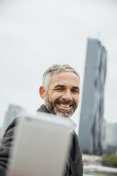 Österreich, Wien, Geschäftsmann macht ein Selfie vor den DC Towers mit seinem Smartphone - AIF000219