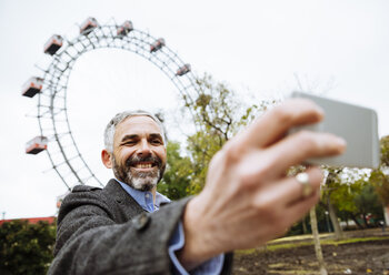 Austria, Vienna, portrait of smiling businessman taking a selfie at Prater - AIF000224