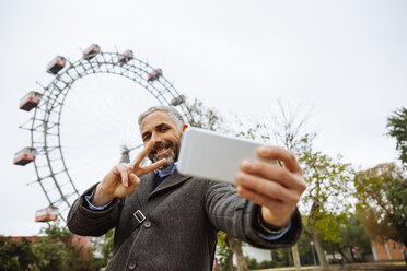 Österreich, Wien, Porträt eines lächelnden Geschäftsmannes, der ein Selfie im Prater macht - AIF000225