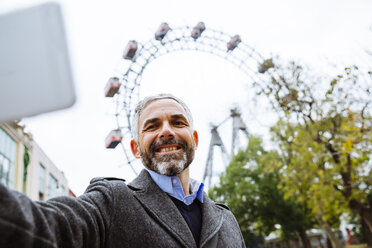 Österreich, Wien, Porträt eines lächelnden Geschäftsmannes, der ein Selfie im Prater macht - AIF000227